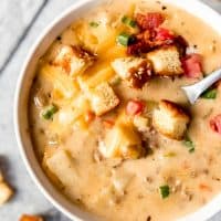 An image of a bowl of cheeseburger soup topped with hamburger bun croutons.