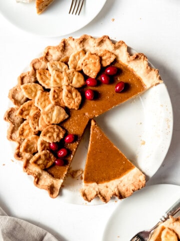 An image of a pumpkin pie with a slice taken out of it.