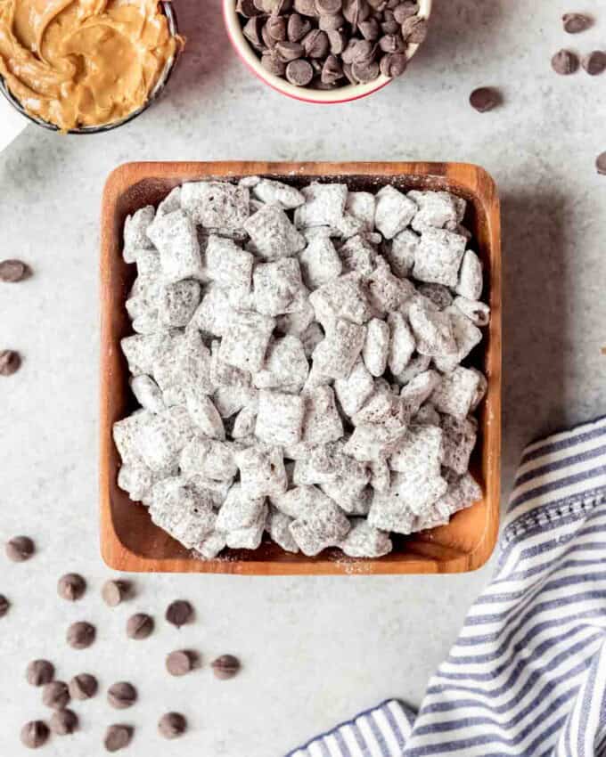 An image of a square wooden bowl filled with the best puppy chow dessert.