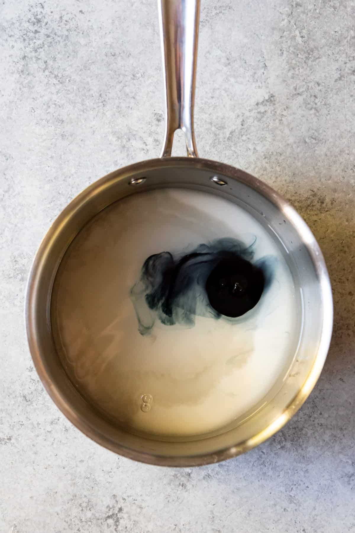 An image of a pan with sugar, corn syrup, water, and black food coloring.