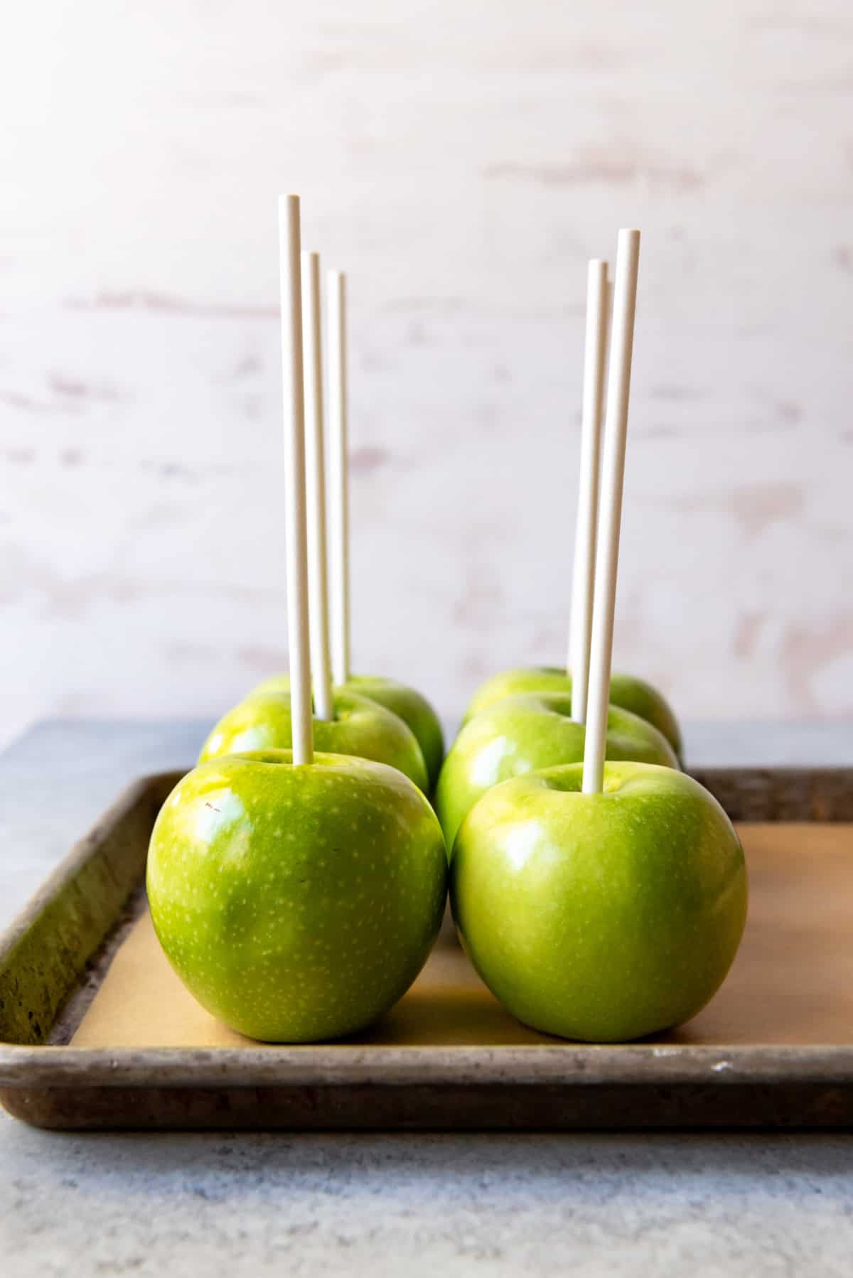 An image of Granny Smith apples with sticks stuck in them. 