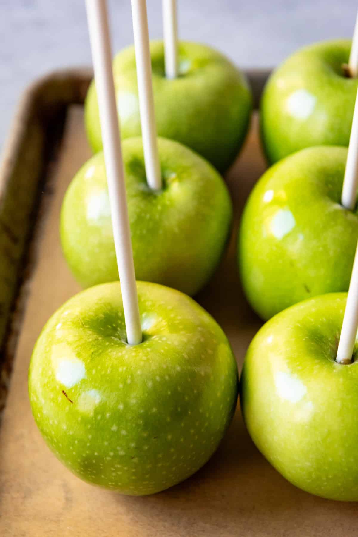 An image of Granny Smith apples with sticks stuck in them. 