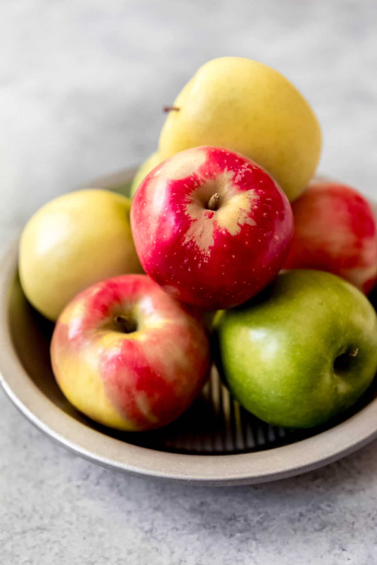 An image of Granny Smith, Pink Lady, and Golden Delicious apples in a pie plate.
