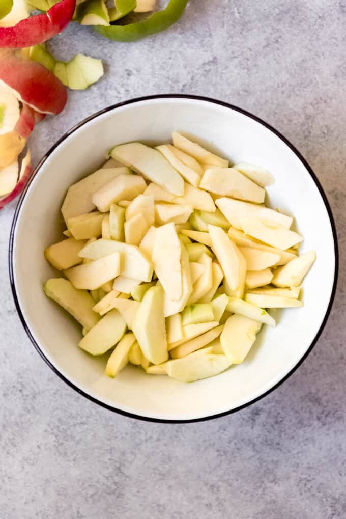 An overhead image of a bowl full of peeled and sliced apples.