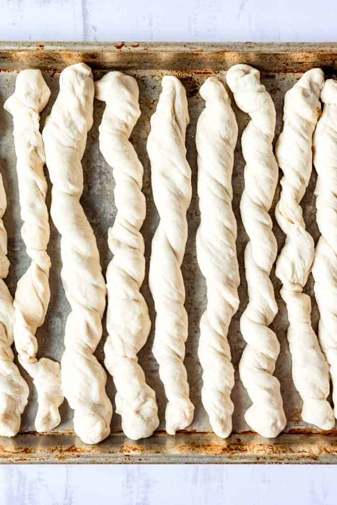 An image of twisted breadstick dough on a baking sheet.