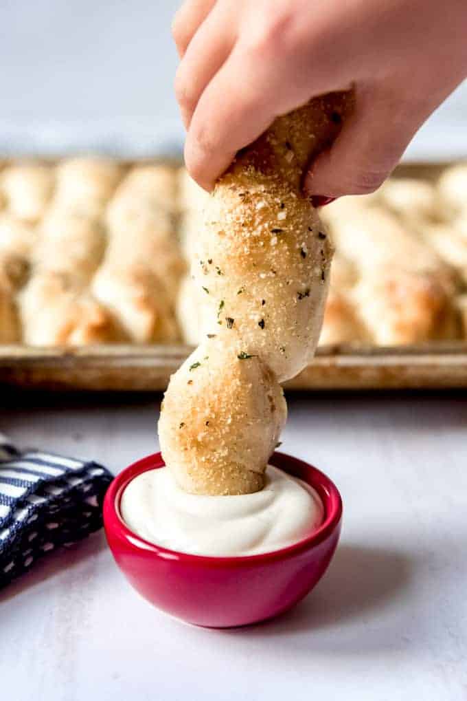 An image of a hand dipping a homemade breadstick into ranch dressing.