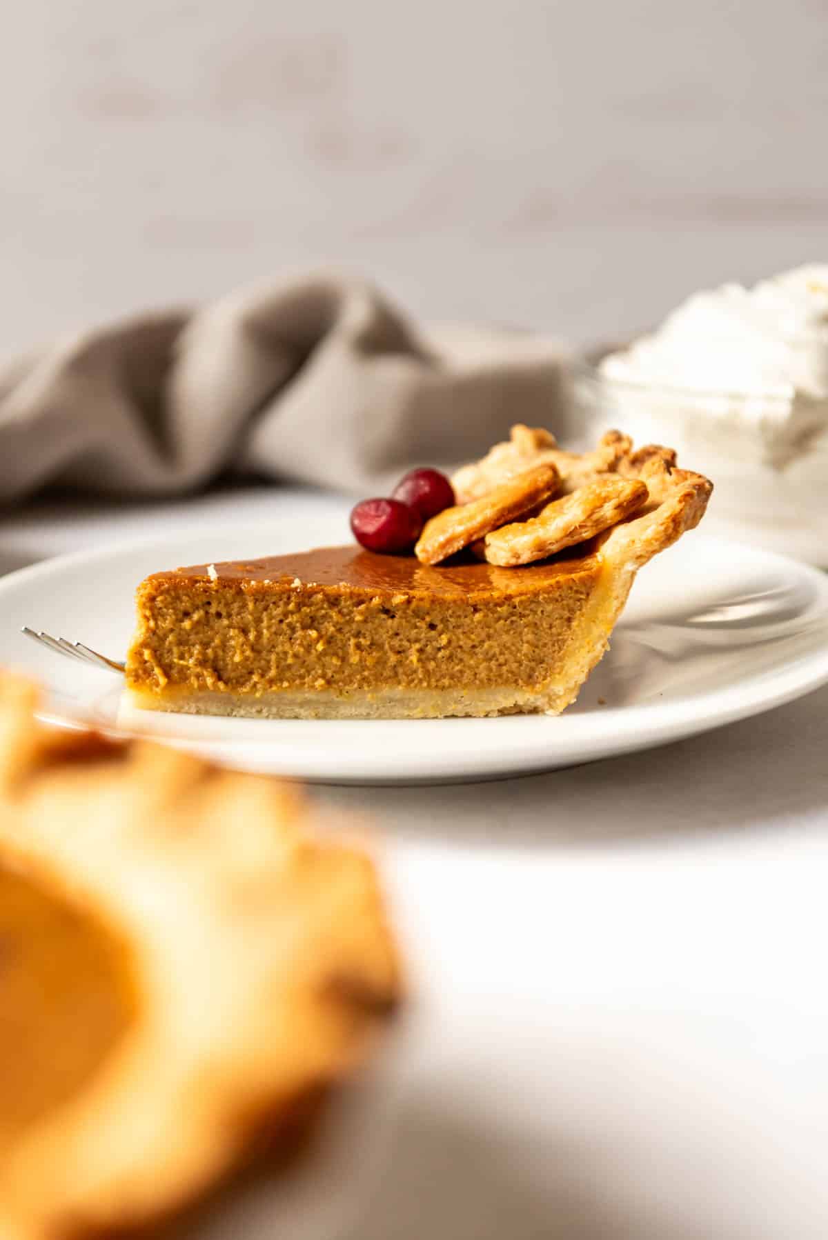 A slice of pumpkin pie on a white plate.