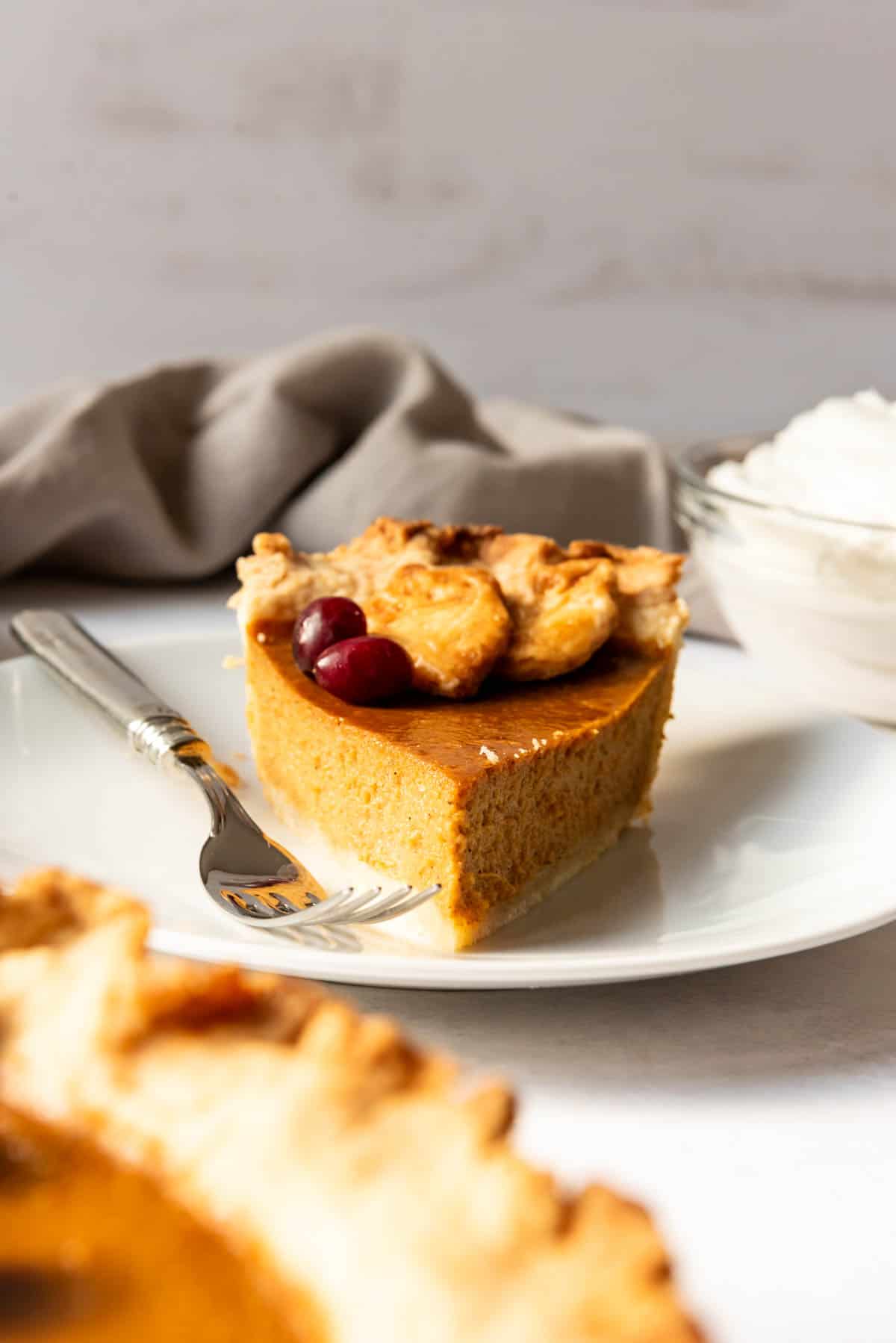An image of a slice of pumpkin pie on a plate with a fork.