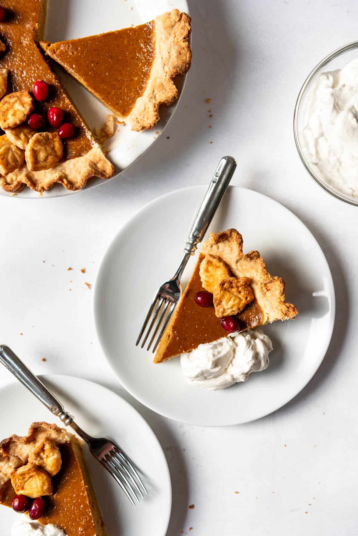 An image of a slice of homemade pumpkin pie on a plate with whipped cream on the side.