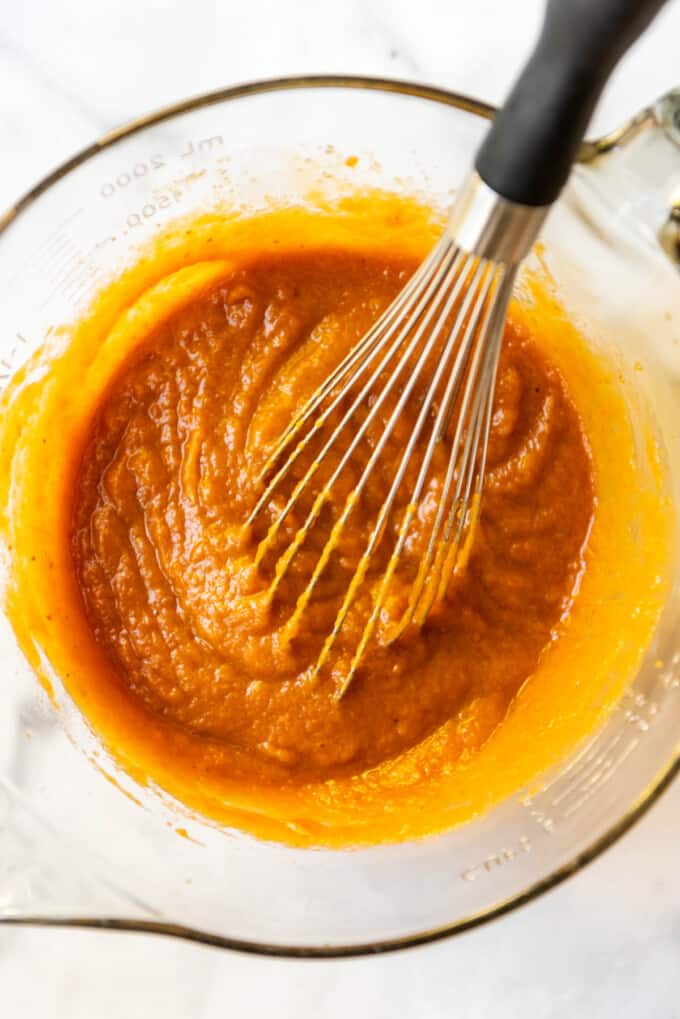Whisking pumpkin pie filling ingredients together in a large bowl.
