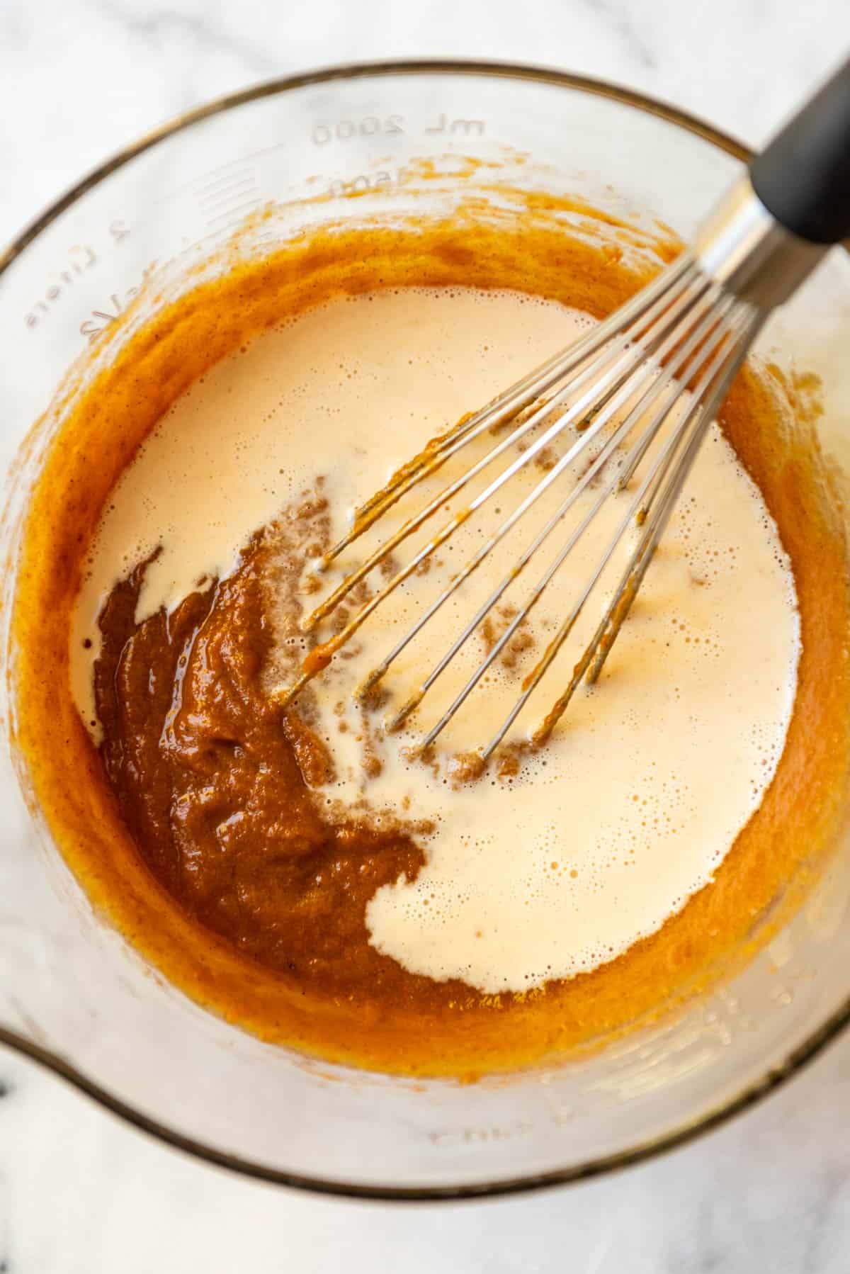 Whisking in evaporated milk to pumpkin pie filling.