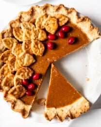 A square overhead image of a homemade pumpkin pie with some slices removed.