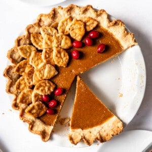 A square overhead image of a homemade pumpkin pie with some slices removed.