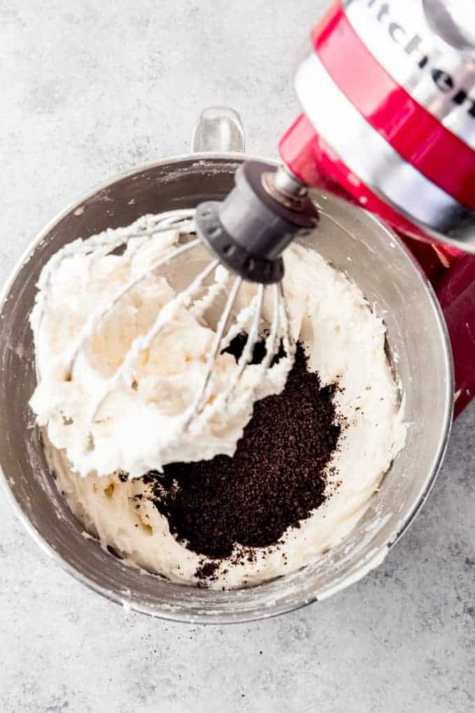 An image of Oreo cookie crumbs being added to a bowl of American buttercream frosting.