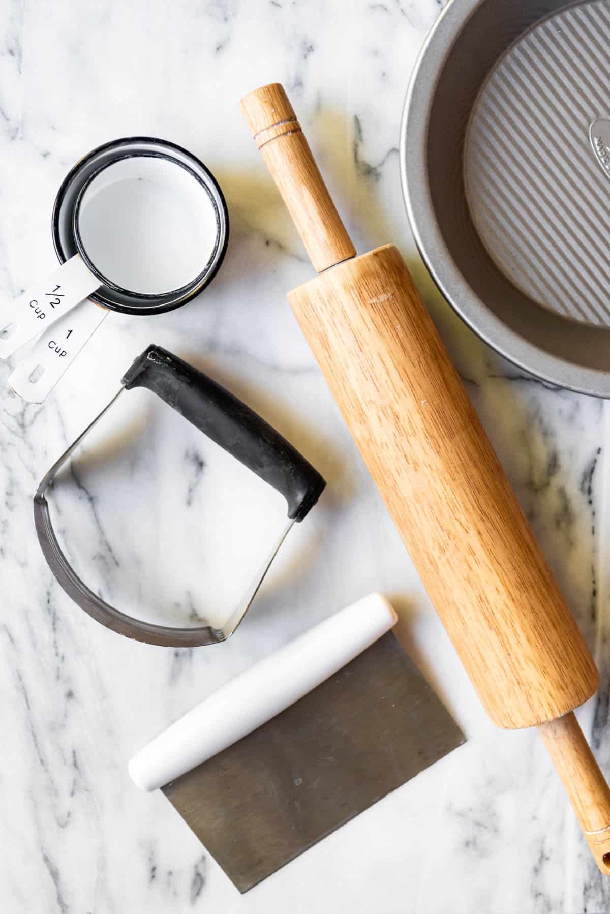 An image of a rolling pin, measuring cups, pastry cutter, pie plate, and bench scraper.