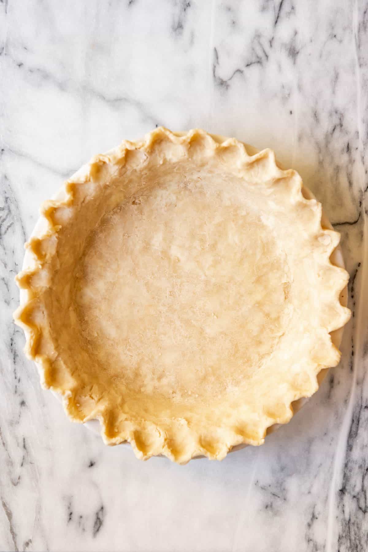 An image of an unbaked pie crust with crimped edges.