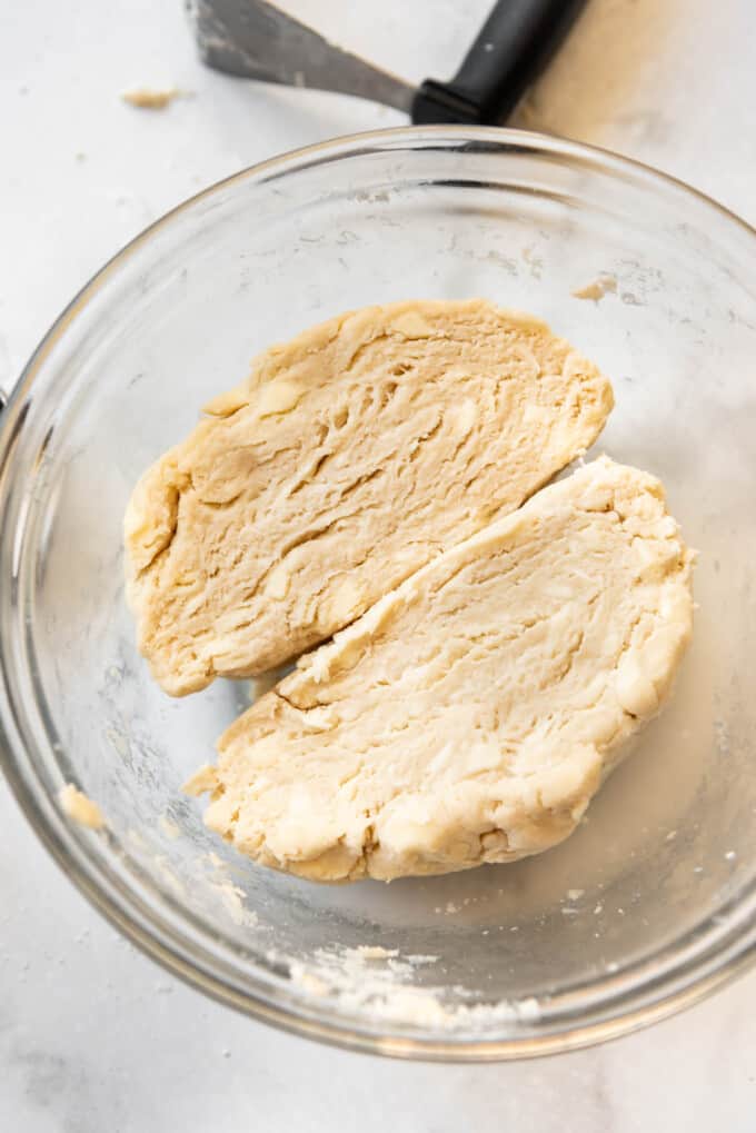 A ball of pie crust dough that has been cut in half to show the flaky layers of butter.