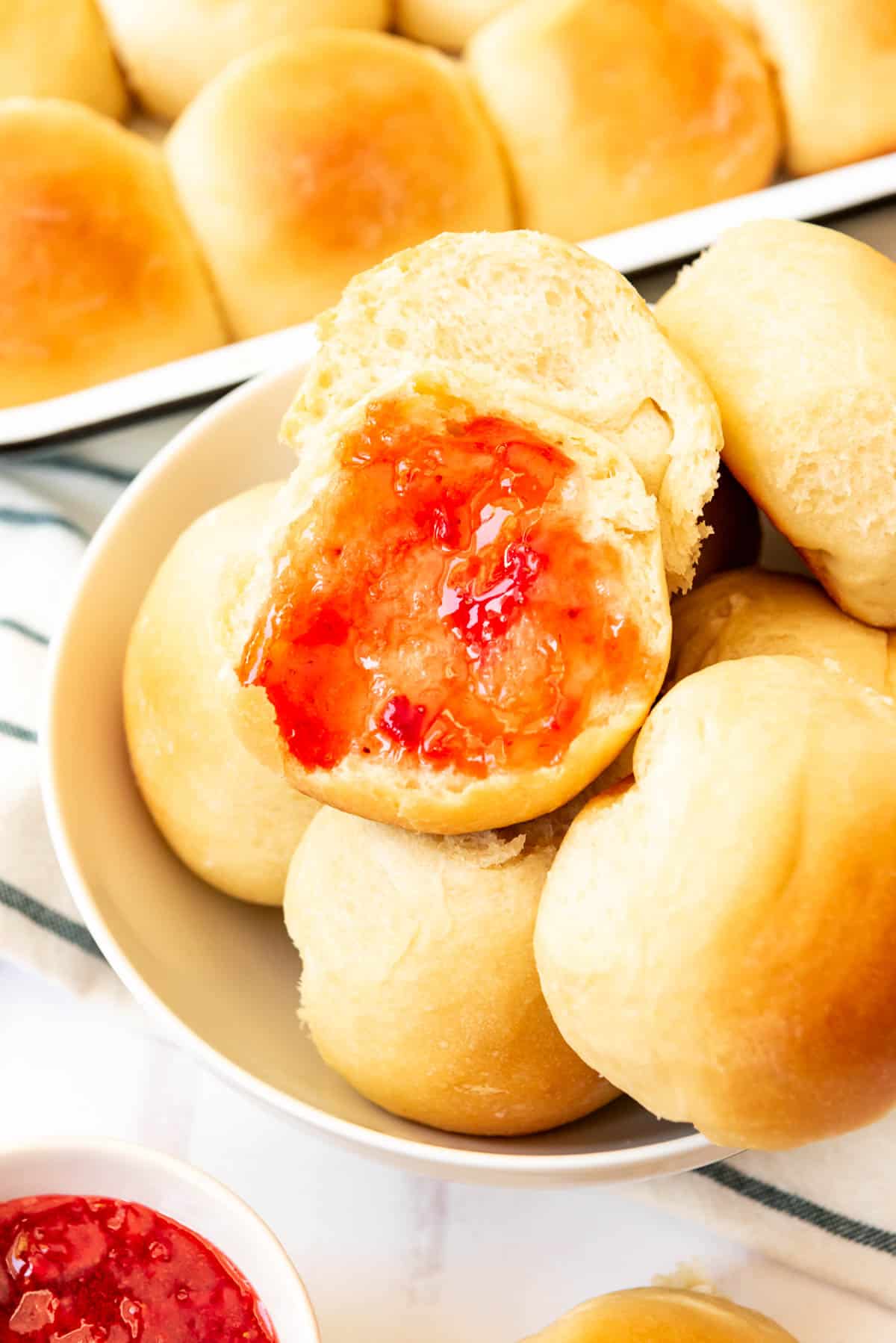 A close image of a potato roll that has been split open and covered in strawberry jam.