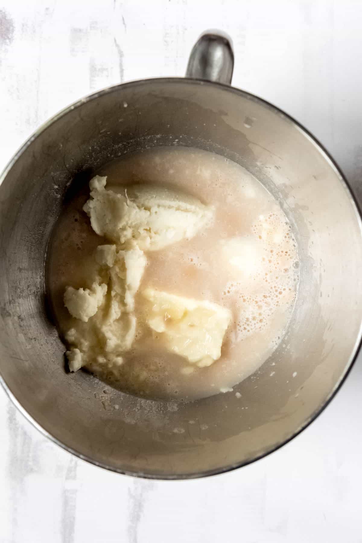 Combining mashed potatoes and proofed yeast in a large mixing bowl.