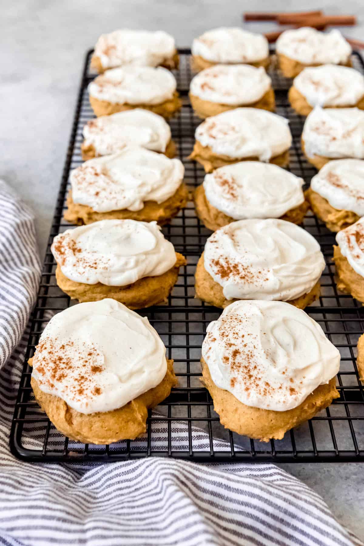 An image of frosted pumpkin cookies on a wire cooling rack.