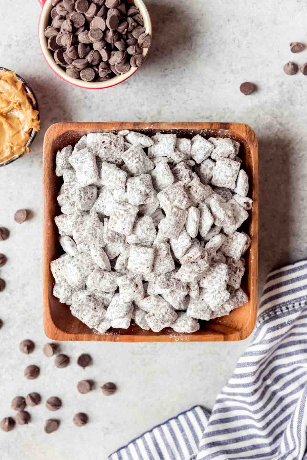 An image of a square wooden bowl filled with the best puppy chow dessert.