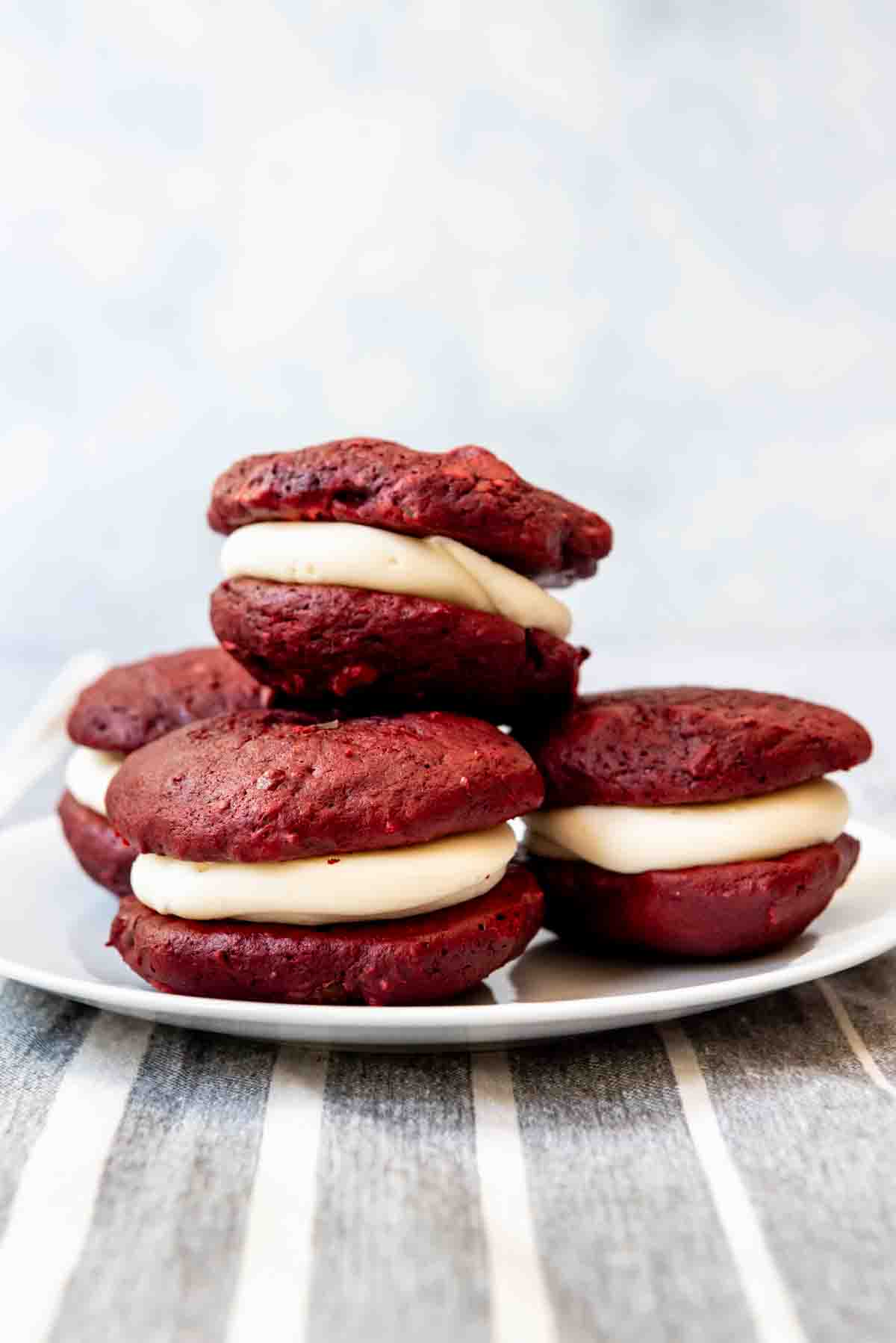 An image of homemade red velvet whoopie pies stacked on a plate.