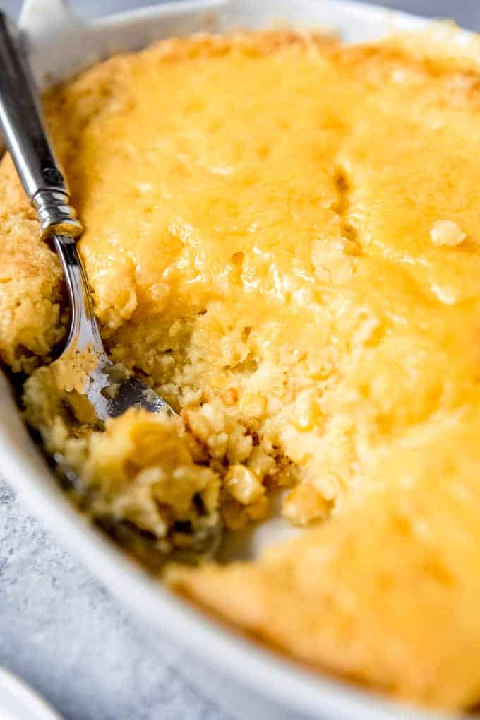 An image of a corn spoon bread casserole with a scoop taken out of it.