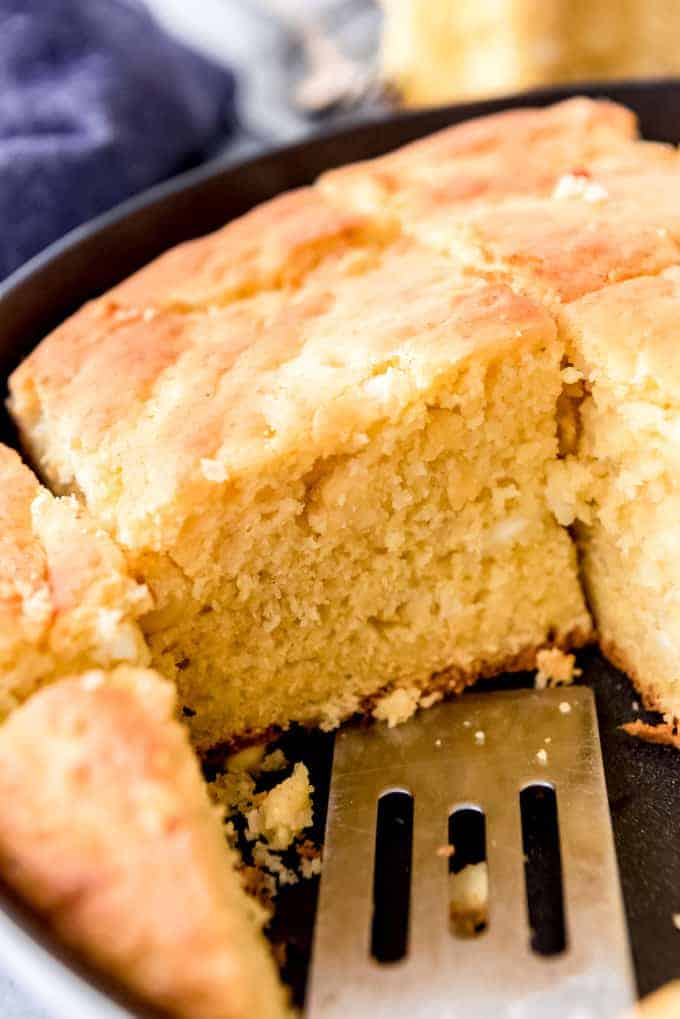 An image of sliced cornbread in a cast iron skillet.