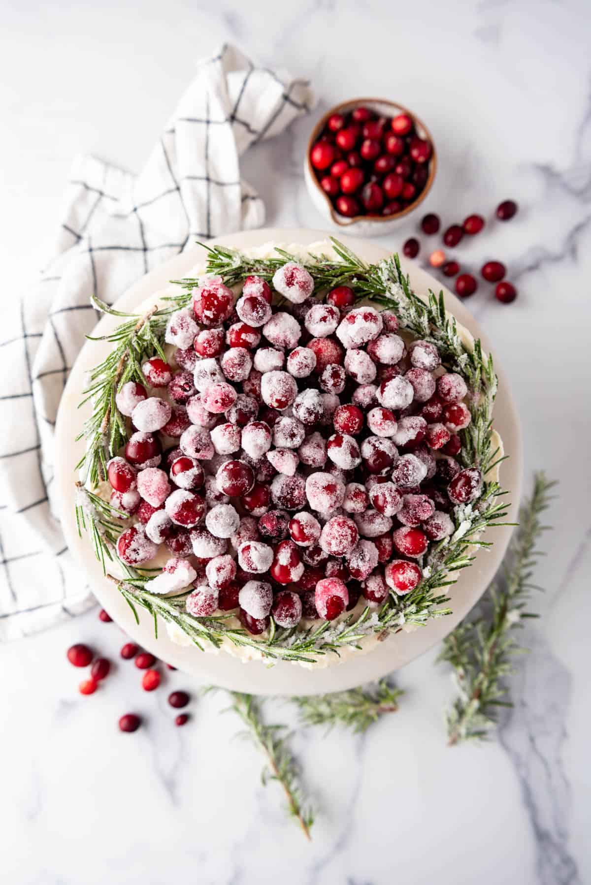 Sugared cranberries and rosemary piled on top of a cranberry cheesecake.