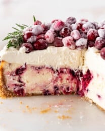 A side angle view of a cranberry cheesecake with a few slices removed.