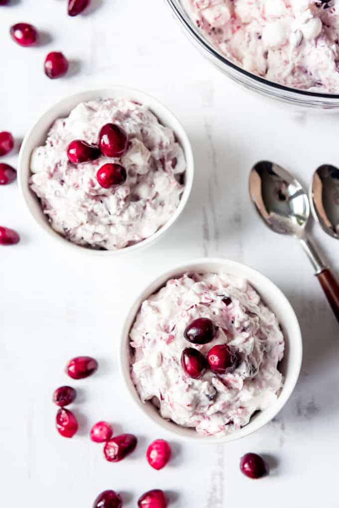 An image of bowls of cranberry fluff salad with fresh cranberries and marshmallows.