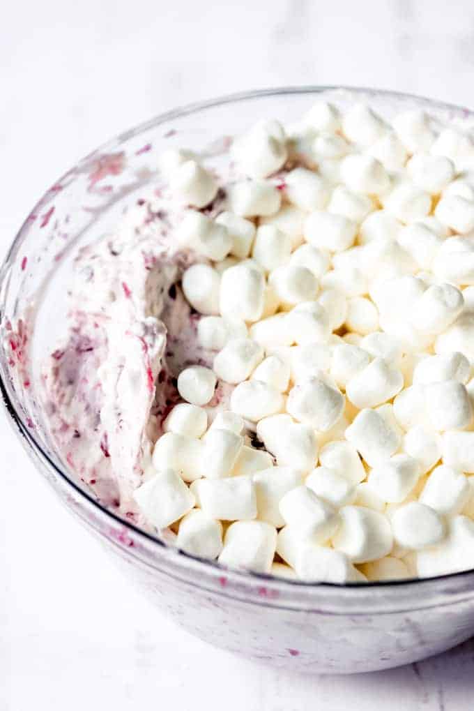 An image of mini marshmallows on top of a creamy fruit salad.