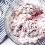 An image of a bowl of fluffy pink dessert salad made with fresh cranberries, pineapple, marshmallows, and whipped cream.