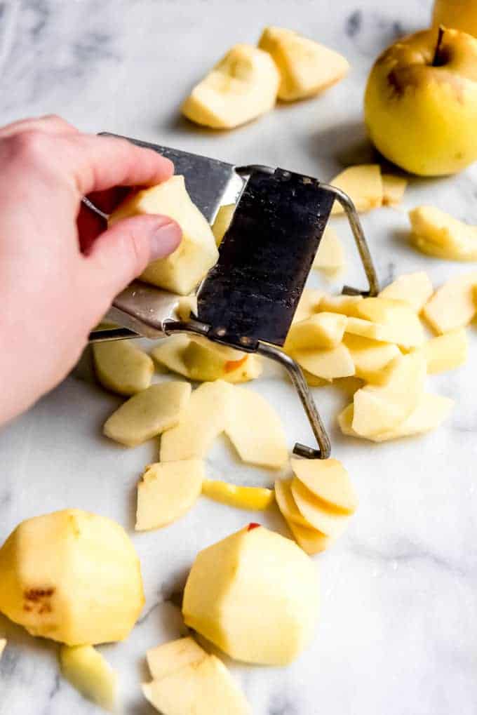 An image of apples being sliced ¼" thick for apple pie using a mandoline slicer.