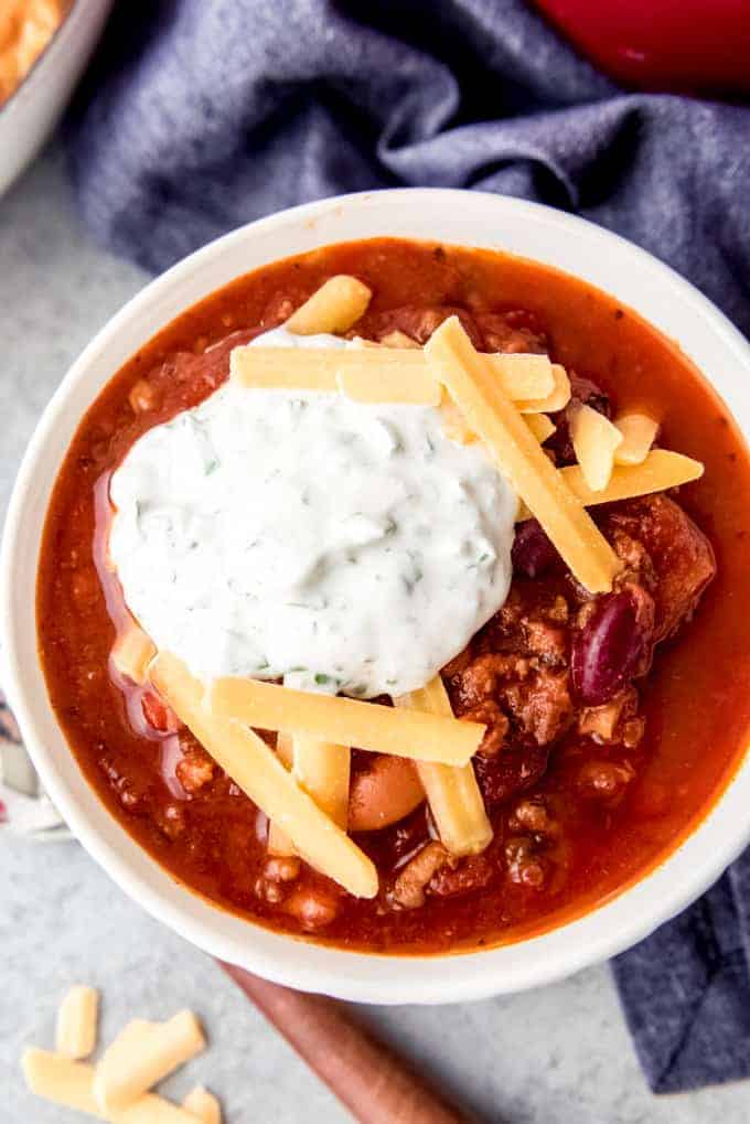 An image of a bowl of homemade chili with shredded cheese and sour cream on top.