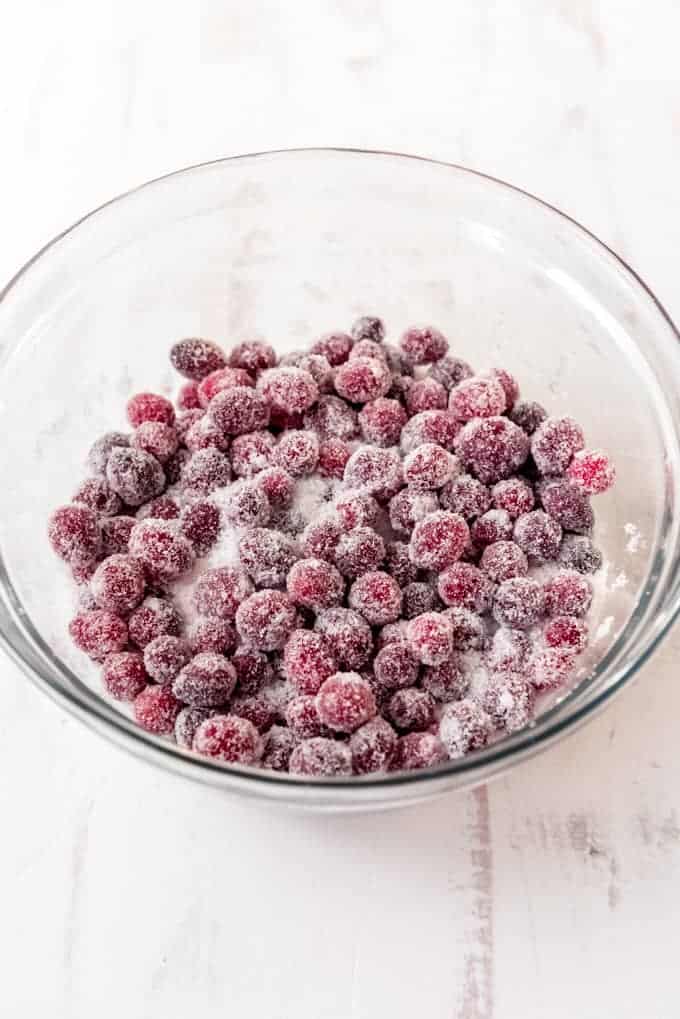 An image of sticky syrup soaked cranberries in a bowl of sugar.