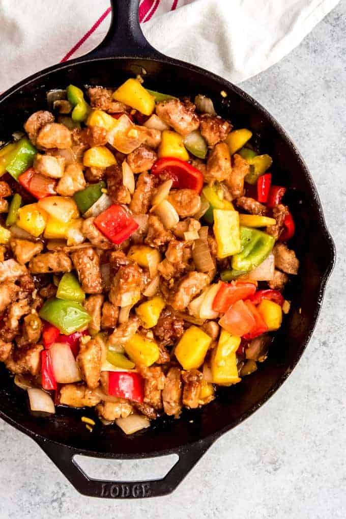 An image of a cast iron skillet filled with homemade sweet and sour pork.