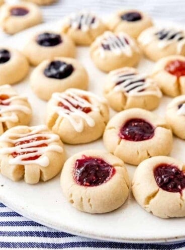 An image of shortbread thumbprint cookies filled with jam and drizzled with glaze.