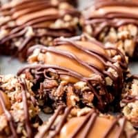 An image of chocolate thumbprint turtle cookies with caramel and pecans.