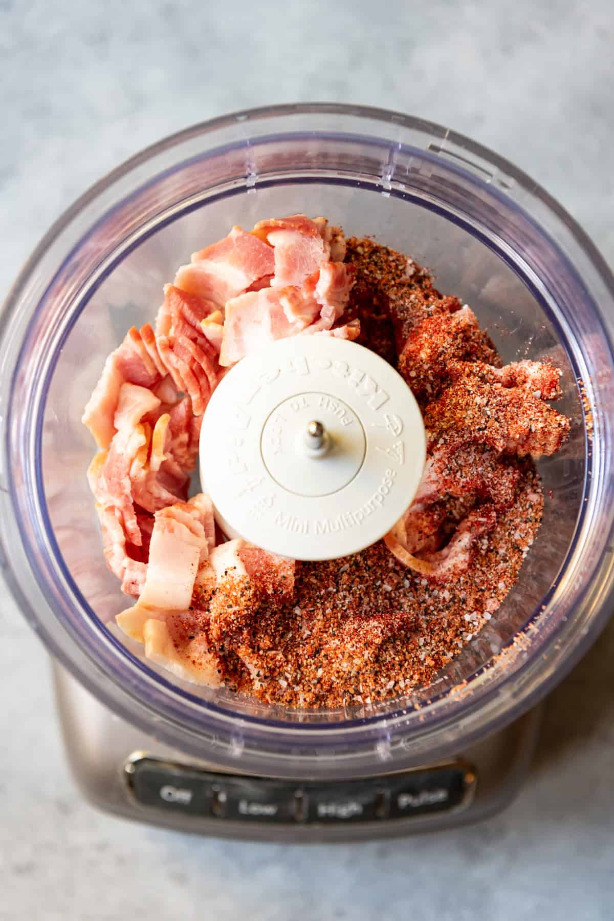 An image of bacon and spices in a food processor.