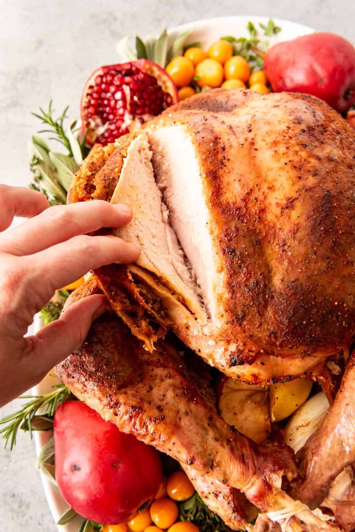 An image of a hand pulling open a sliced turkey breast to show how moist it is inside.