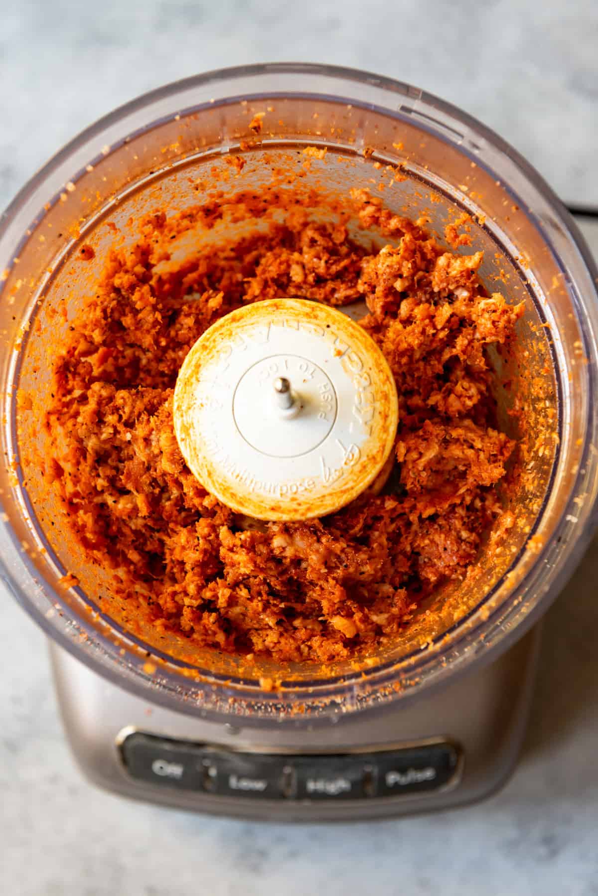 An image of chopped bacon and spices in a food processor.