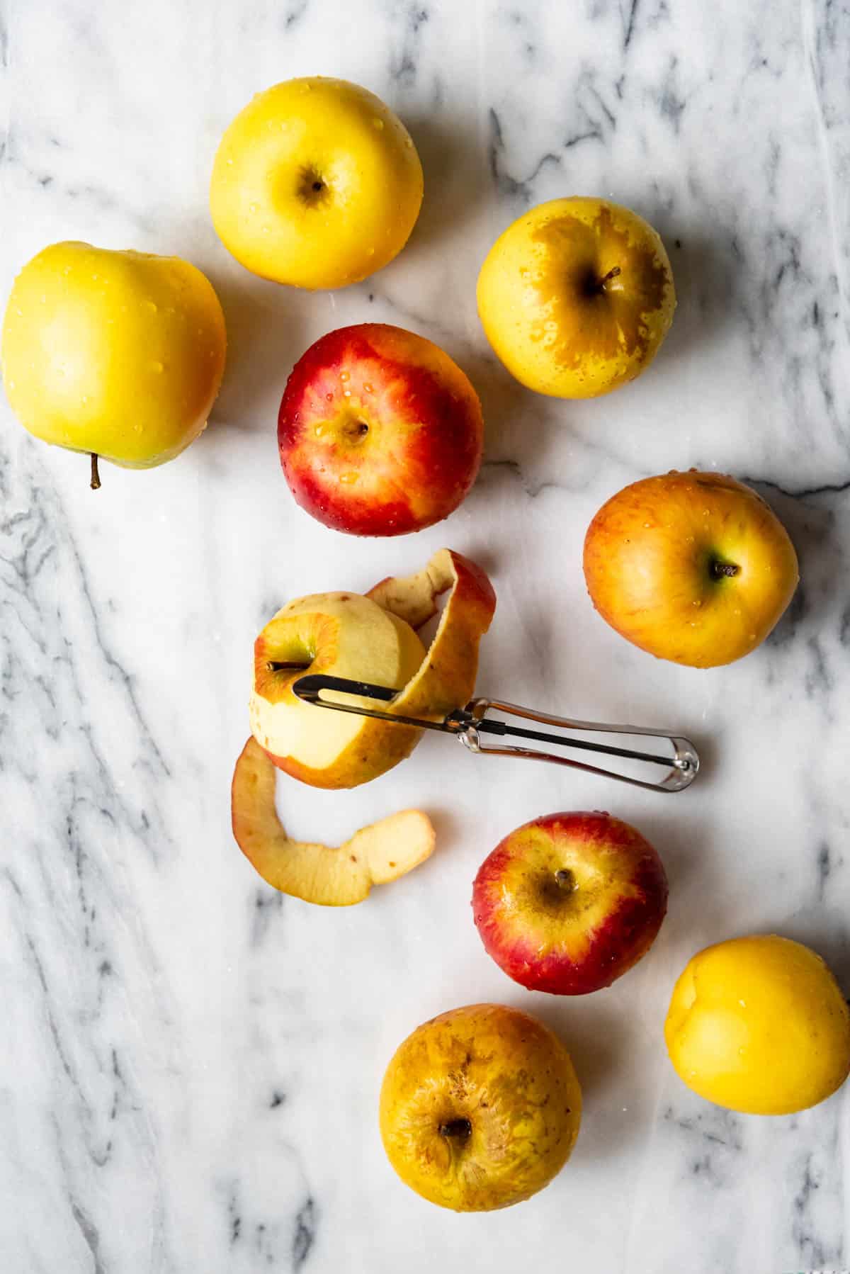 An image of red and yellow apples with an apple peeler.