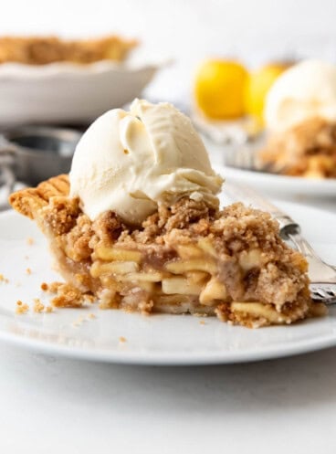 An image of a slice of dutch apple pie with a scoop of vanilla ice cream.