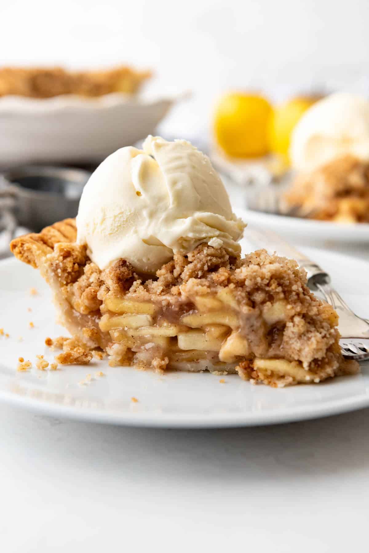 An image of a slice of dutch apple pie with a scoop of vanilla ice cream.