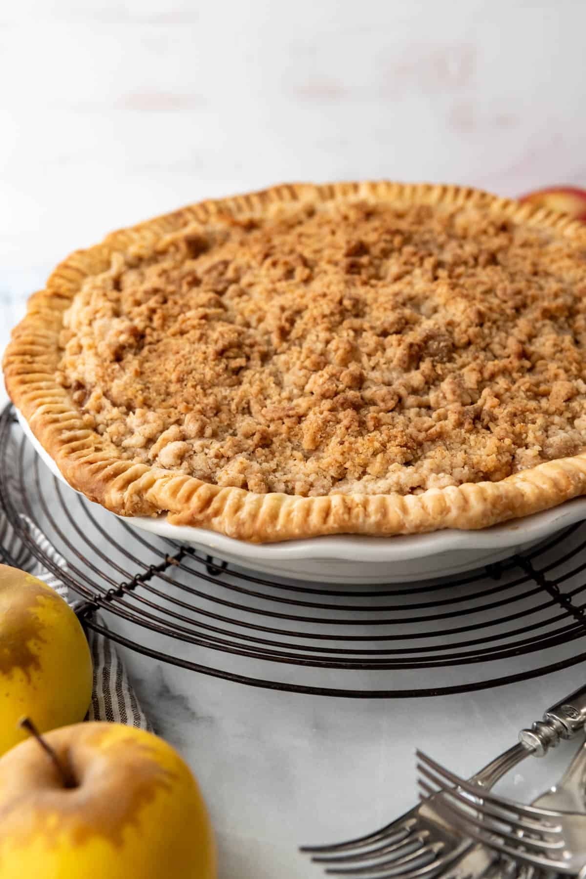 An image of an apple pie with a crumble topping cooling on a wire rack.