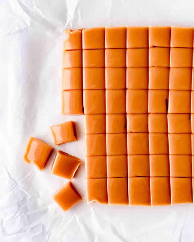 An image of a large piece of homemade caramel being cut into smaller squares.