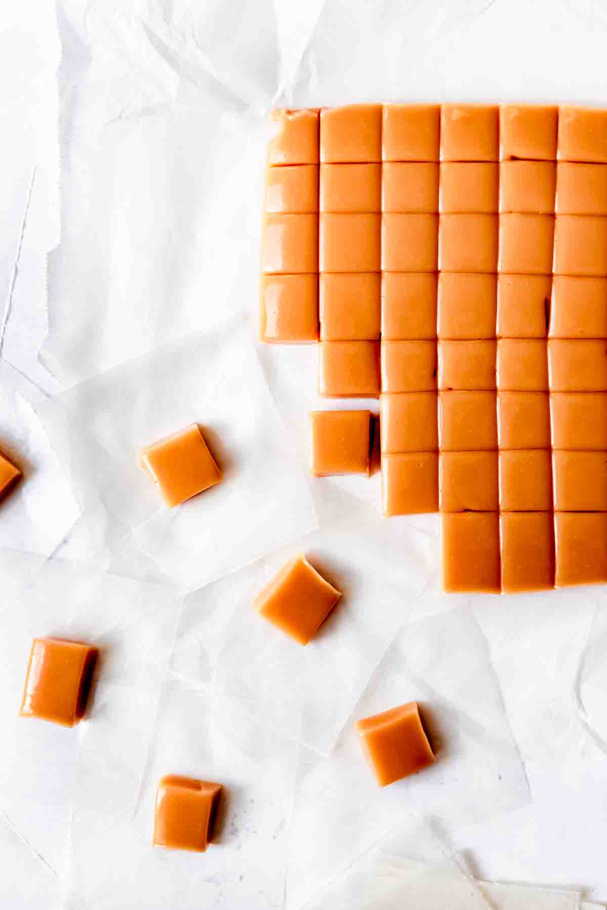 An image of a large piece of homemade caramel being cut into smaller squares.