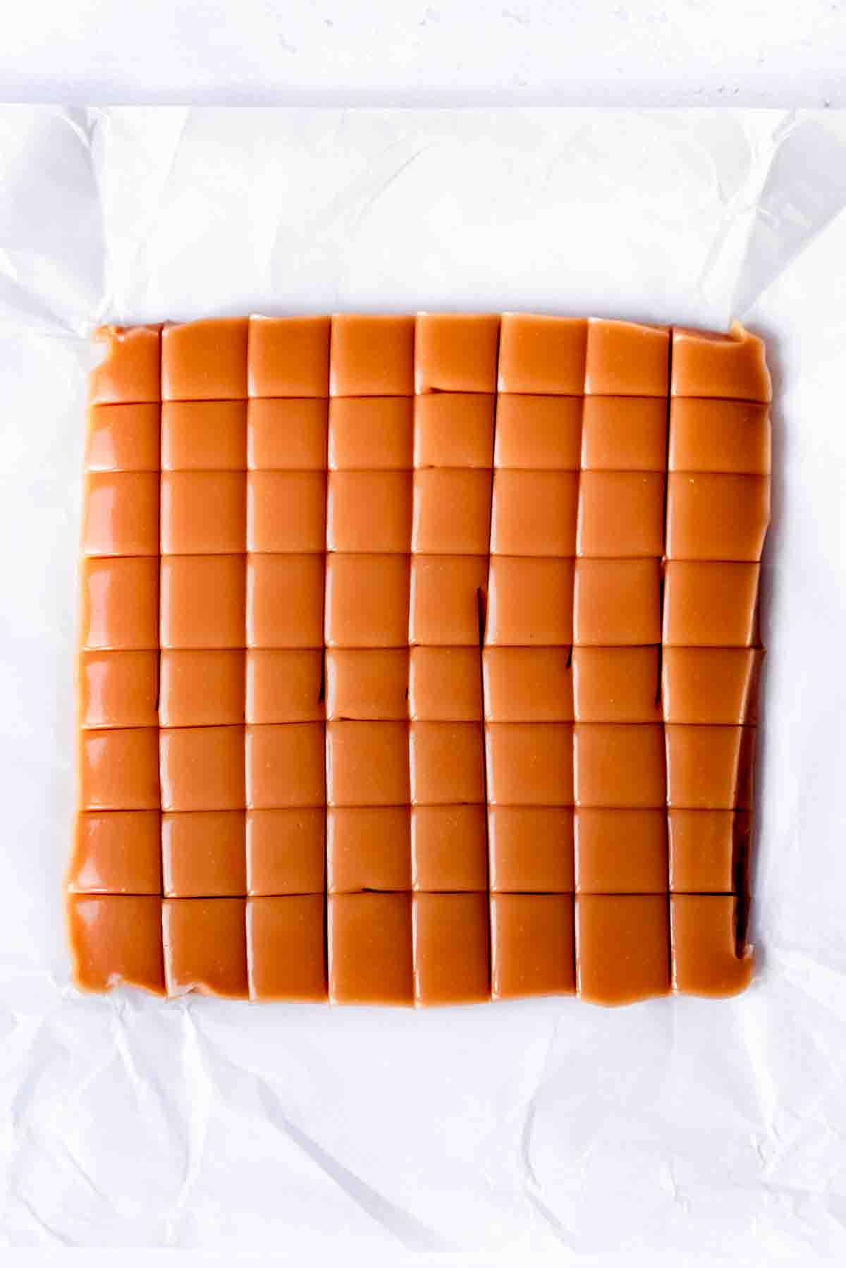 An overhead image of a batch of homemade caramels that have been cut into squares.