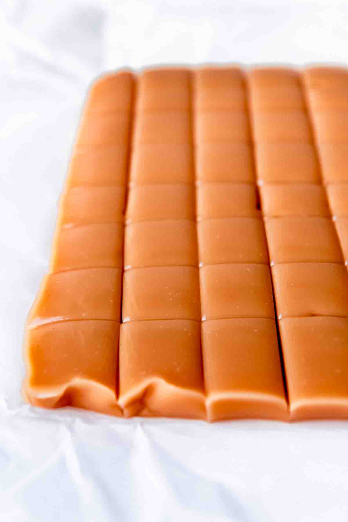 An image of a bar of caramel being sliced into squares.